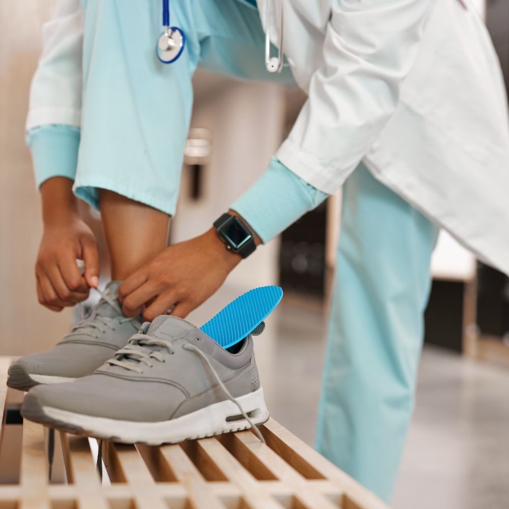 A doctor with Naboso's blue activation insoles in his shoes lacing them up before a day of work